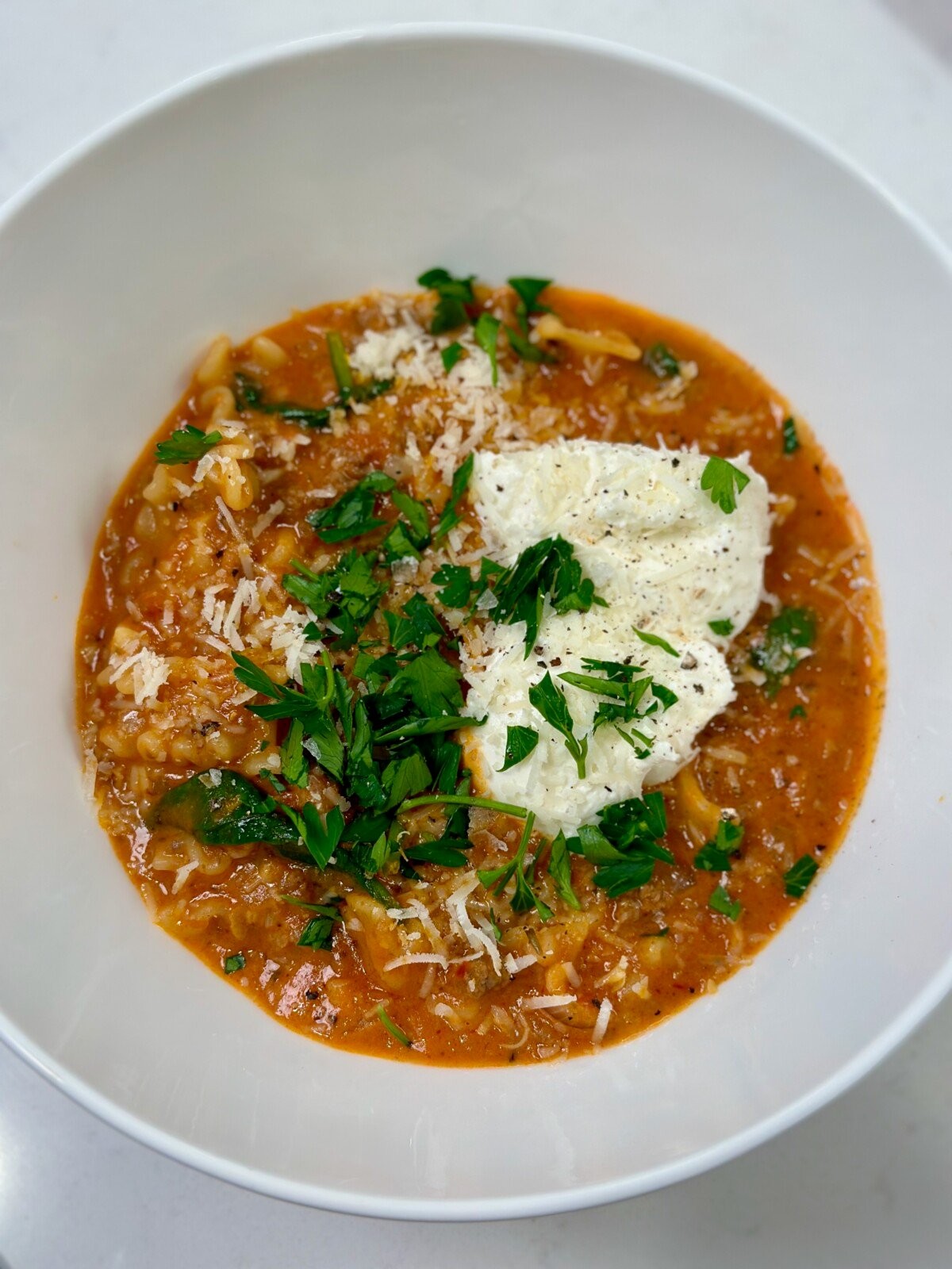 bowl of creamy lasagna soup with ricotta dollop and basil