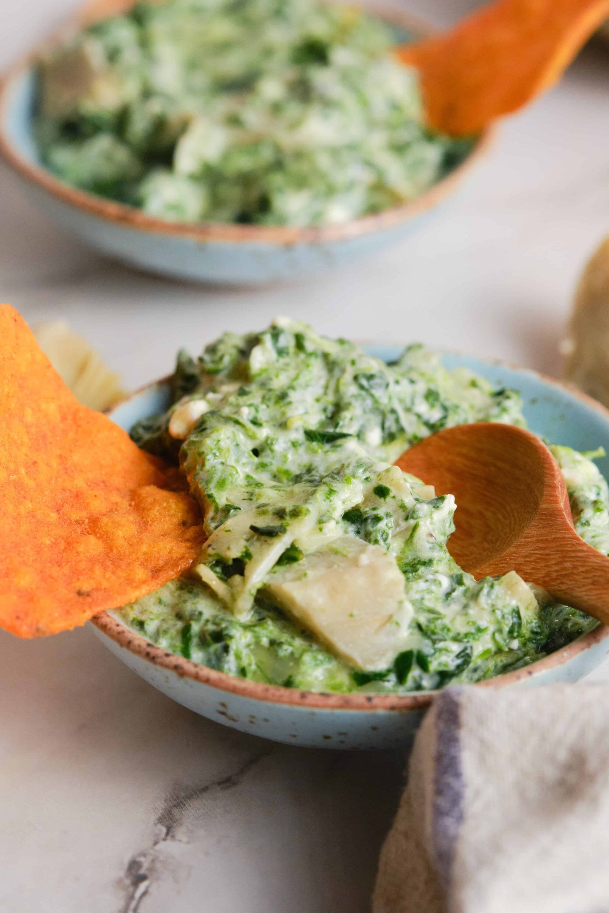 Creamy spinach artichoke dip in a rustic bowl with tortilla chips
