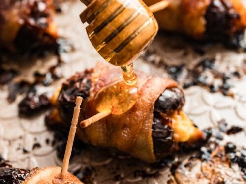 Close-up of golden, sticky bacon wrapped dates on a rustic wooden board