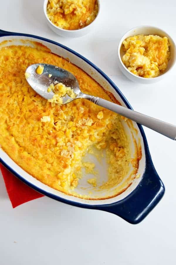 warm, golden corn casserole with a spoon, steam rising, rustic table setting