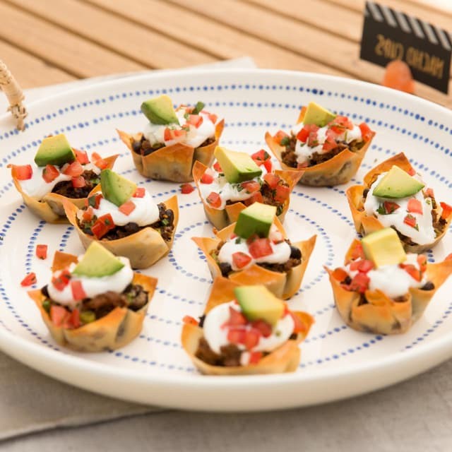 Vibrant loaded nacho cups on a rustic wooden table, overhead shot, colorful party food