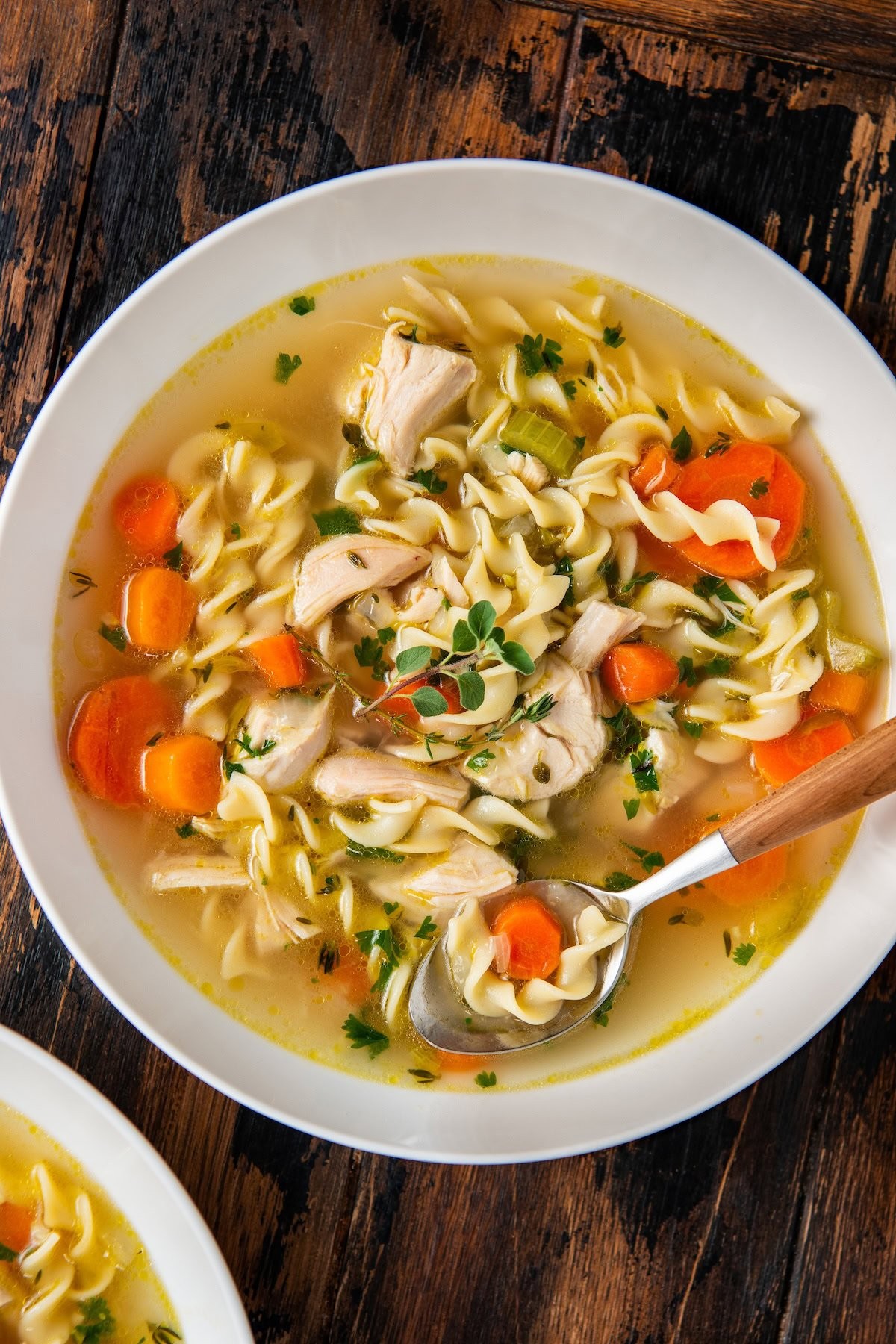 A pot of simmering chicken noodle stew on a rustic wooden table