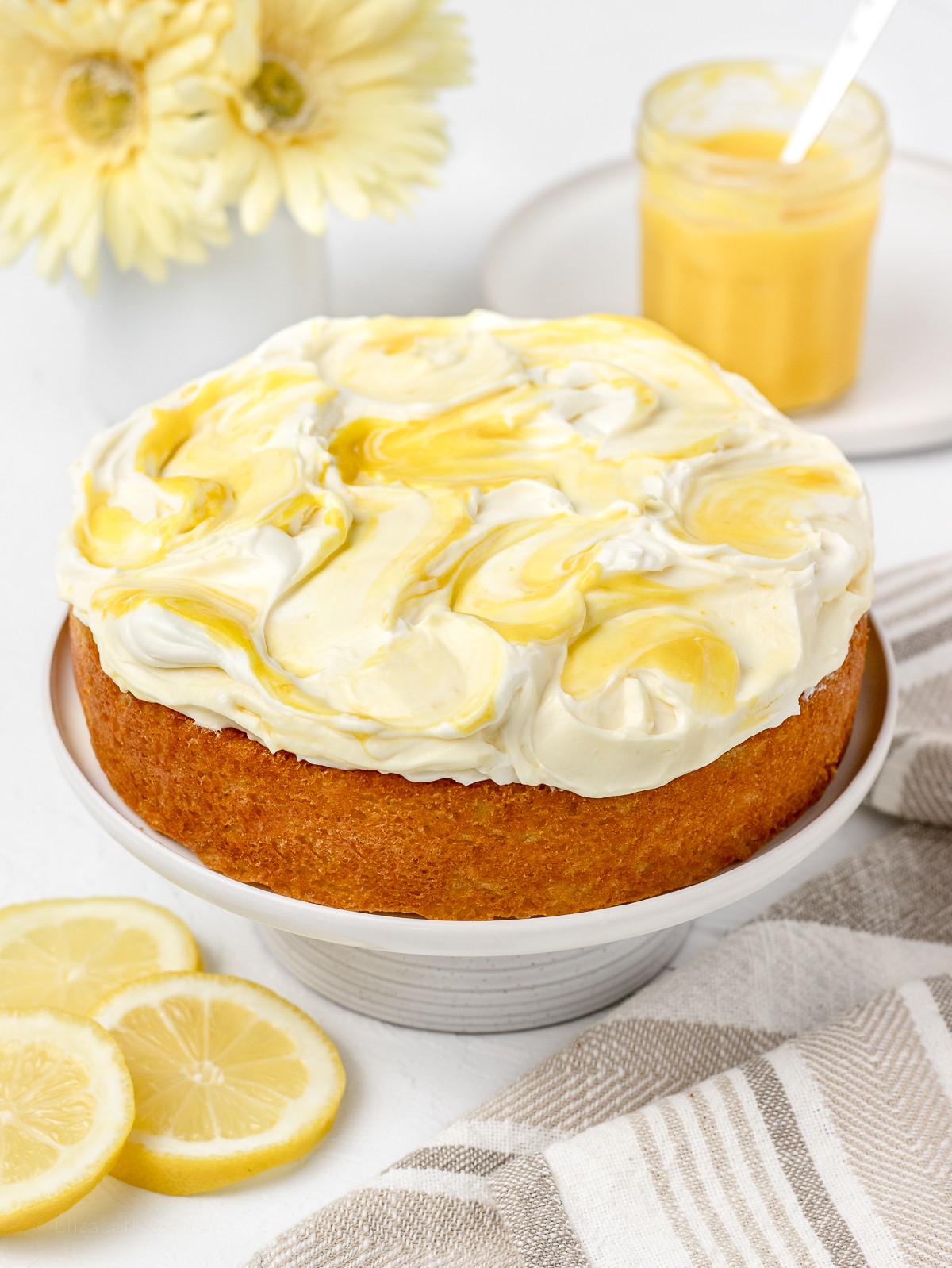 Close-up of a beautifully sliced lemon yogurt cake on a white plate with a lemon slice garnish