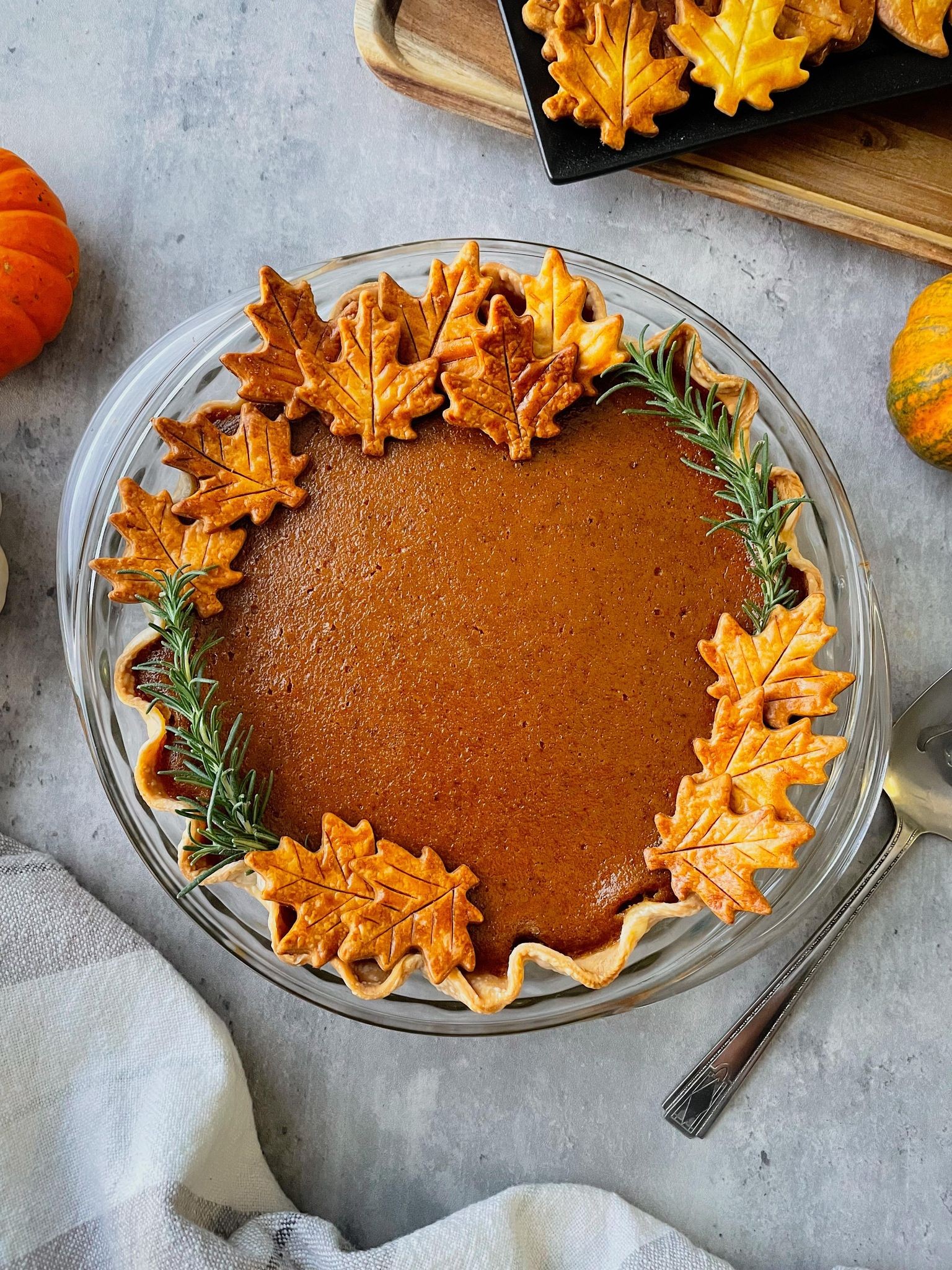 Rustic brown sugar pumpkin pie with a golden crust, surrounded by autumn leaves and warm spices like cinnamon sticks and star anise, soft focus background.