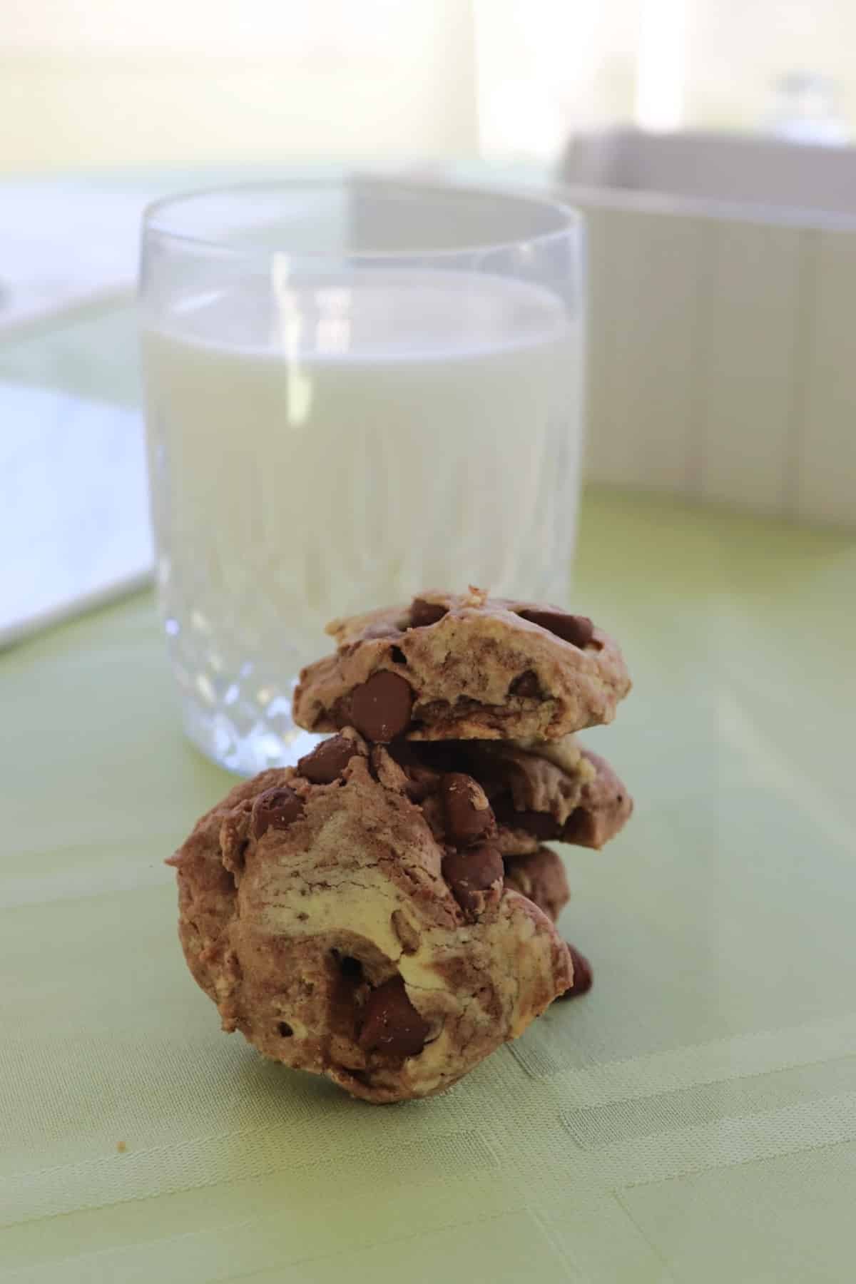 A close-up of a stack of chewy chocolate marble cookies with a glass of milk
