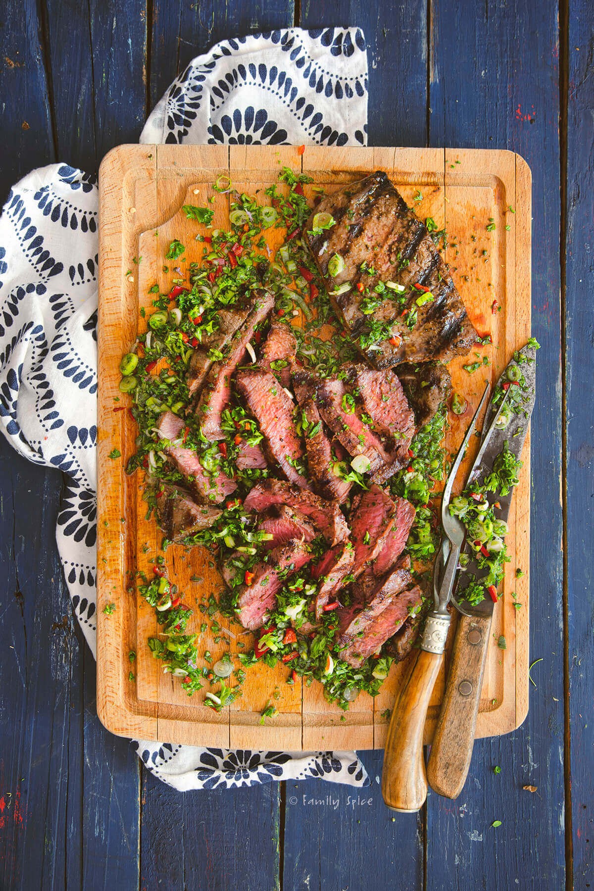 garlic herb roasted flank steak on a wooden cutting board