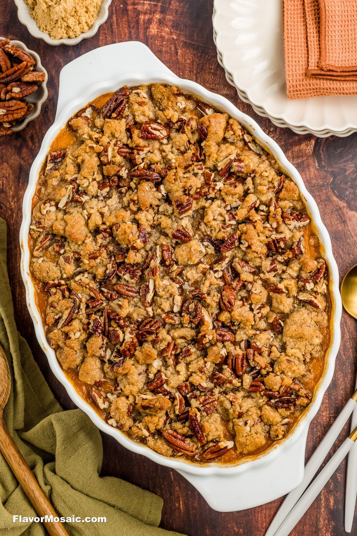 Golden sweet potato casserole with a thick cinnamon streusel topping, garnished with pecans, in a festive setting