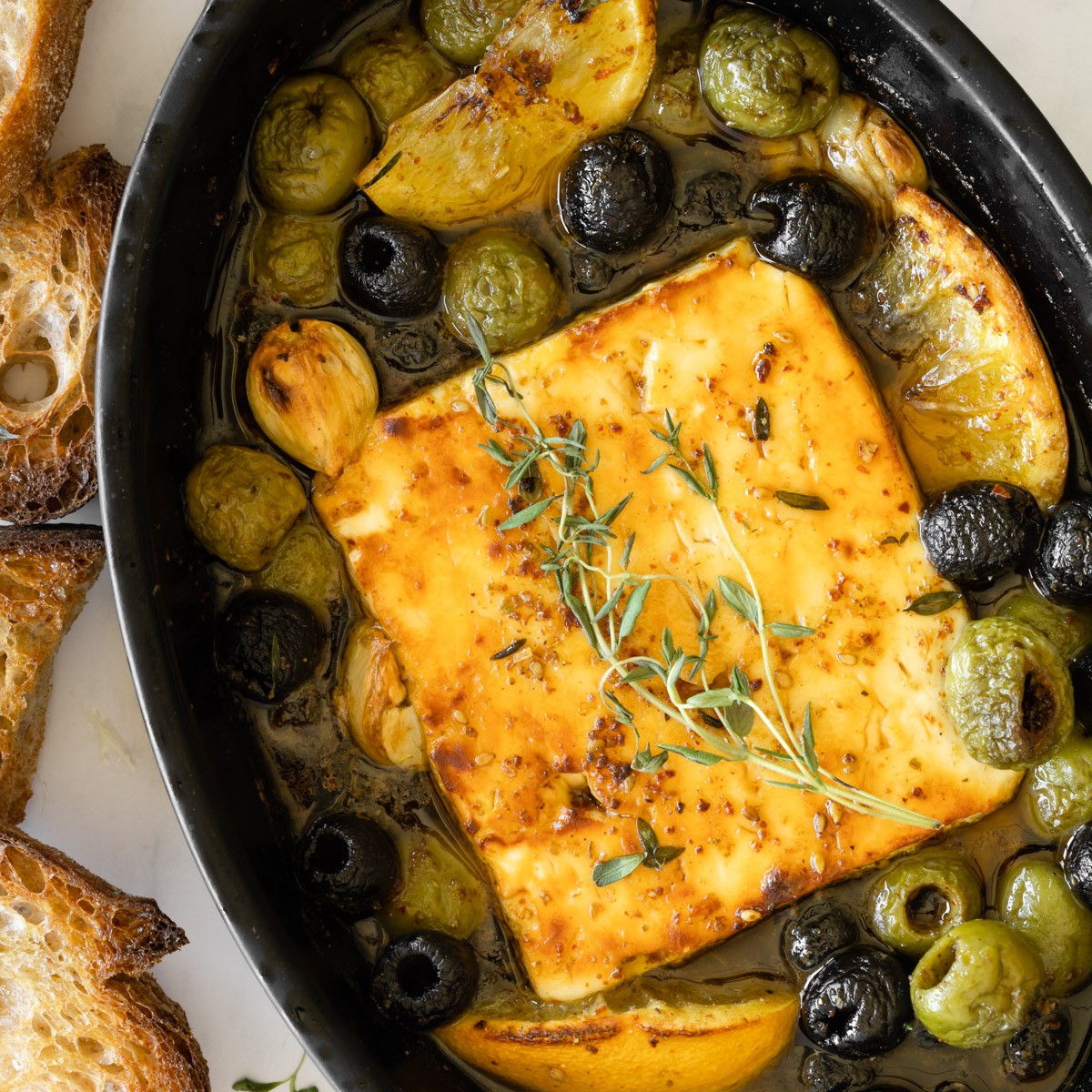 rustic baked feta with olives and fresh herbs, golden brown