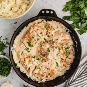 overhead shot of creamy white garlic chicken in a slow cooker, garnished with fresh parsley