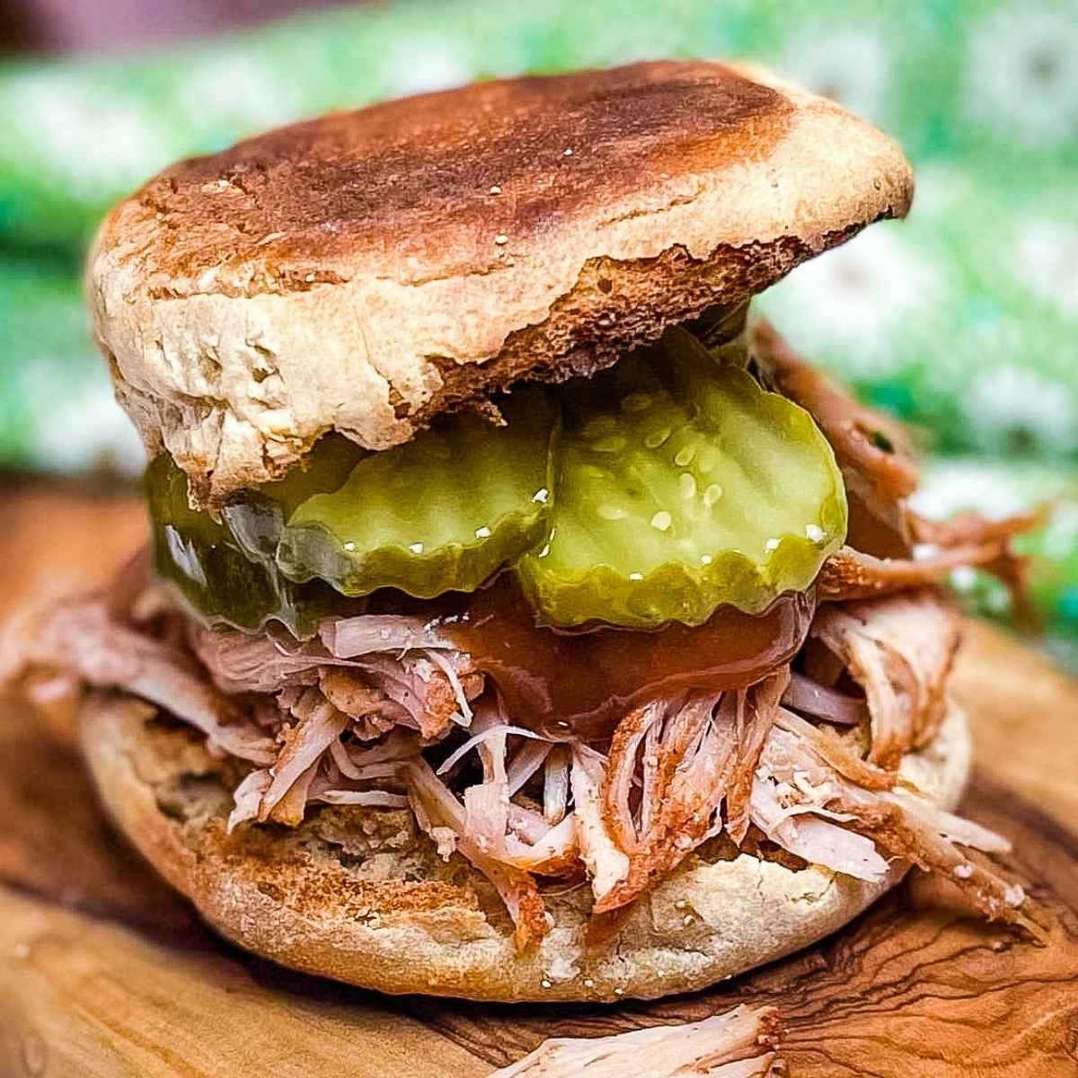 mouthwatering pulled pork sandwich on a rustic wooden board, slow cooker in background, natural lighting