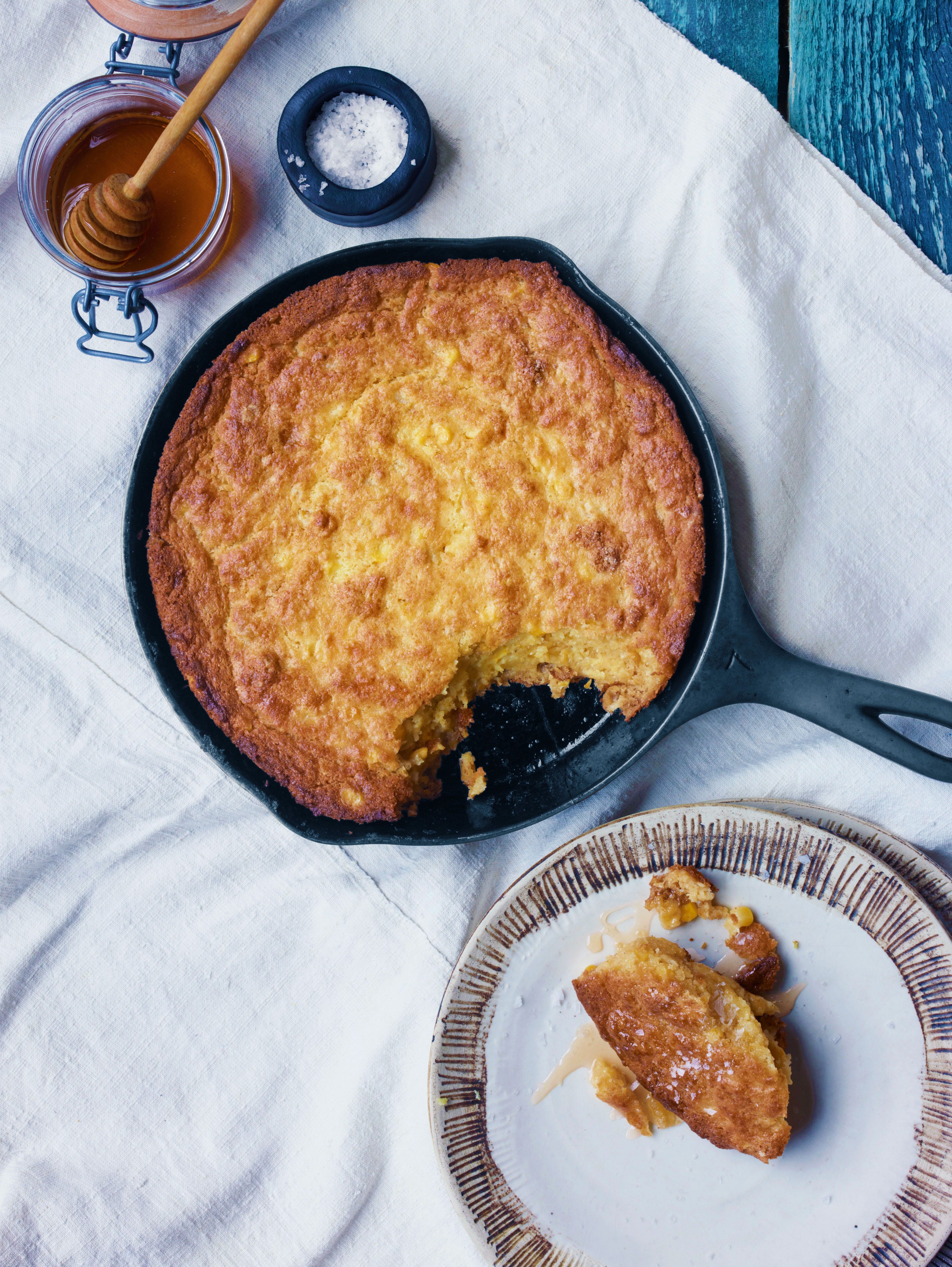 Rustic corn casserole baking in a cast iron dish, golden brown top, steam rising