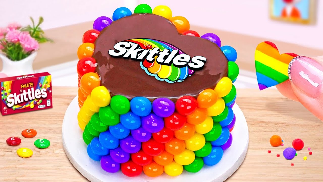A vibrant spectrum cake decorated with toys and candies