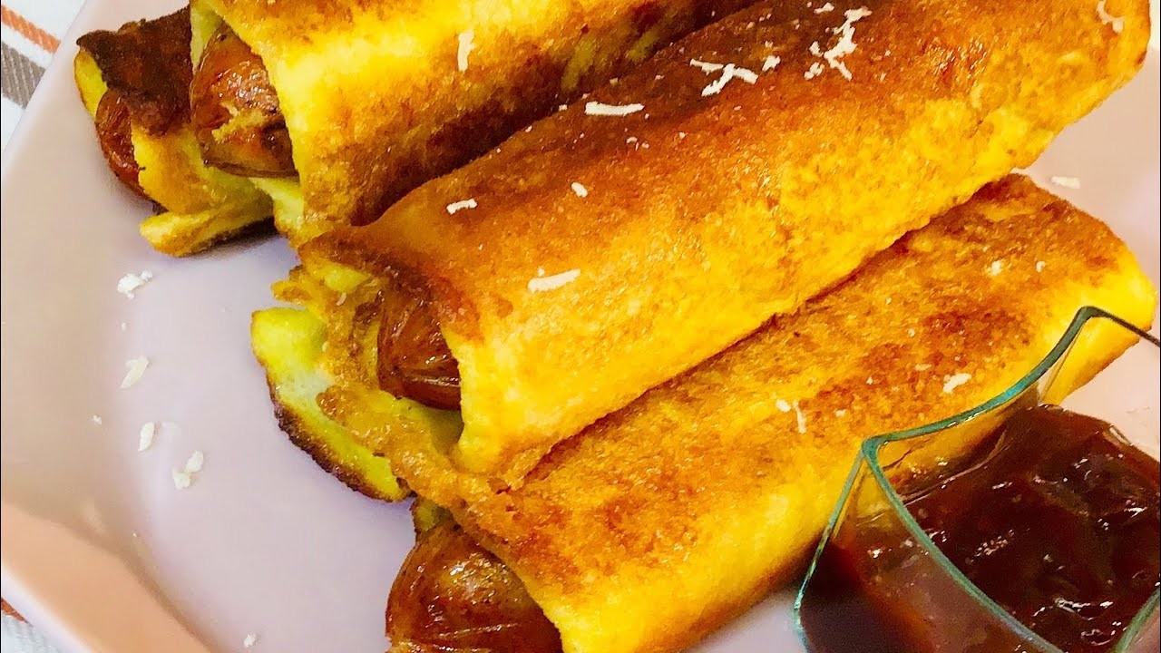 golden baked sausage egg breakfast roll ups on a rustic wooden board, garnished with fresh chives, a cup of coffee in the background