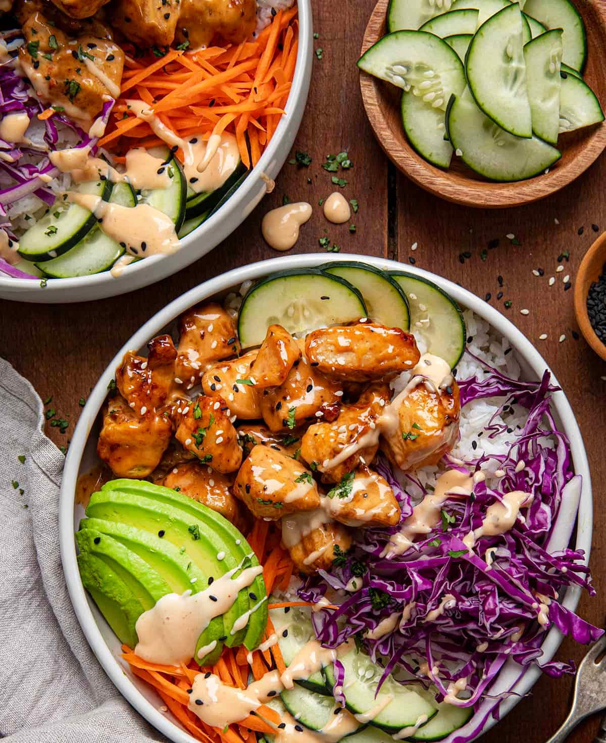 Vibrant Bang Bang Chicken Bowl with a glossy sauce, colorful vegetables, and crispy chicken pieces, served over rice with a sprinkle of sesame seeds and green onions, overhead shot