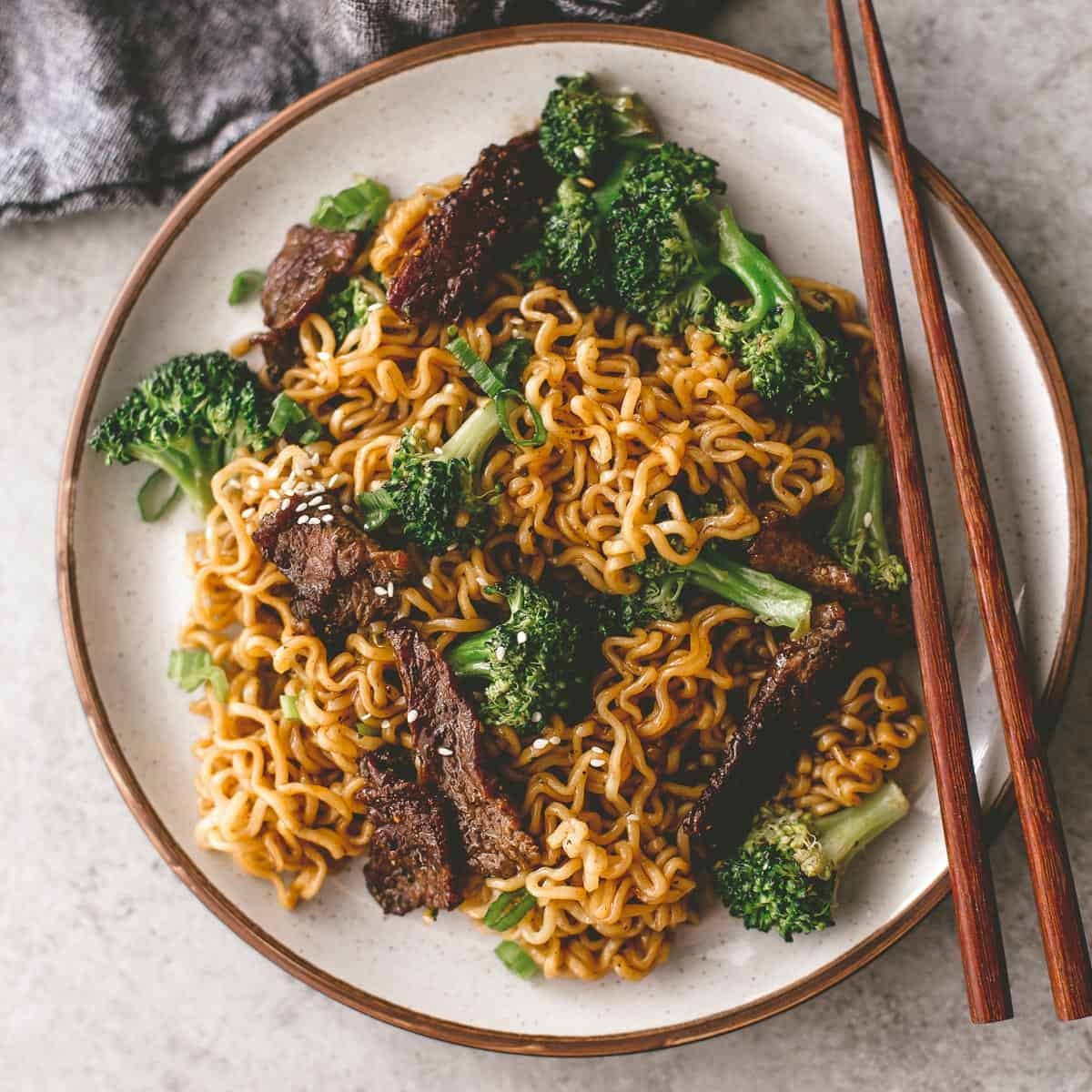 A bowl of beef and broccoli ramen with chopsticks