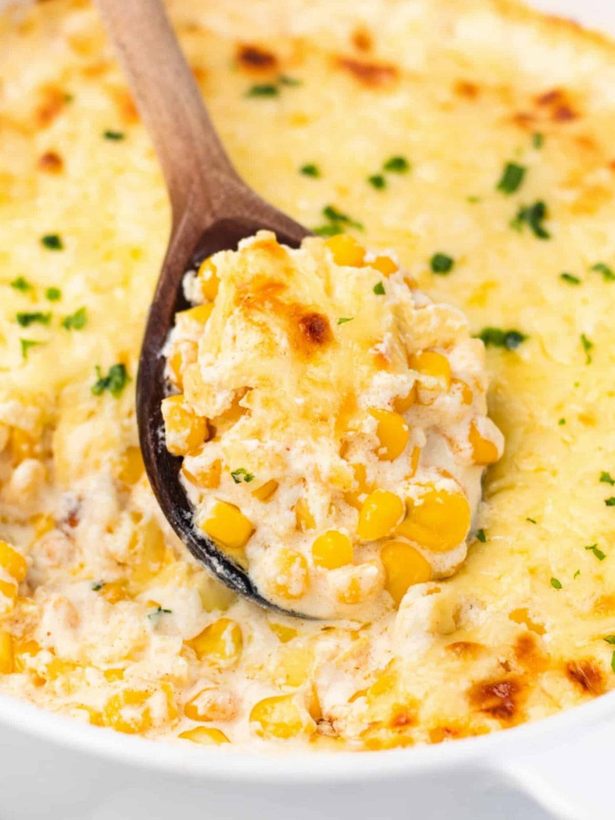 Delicious golden baked corn casserole with creamy texture and a rich, golden top, garnished with fresh chives, in a rustic serving dish on a wooden table, cozy lighting.
