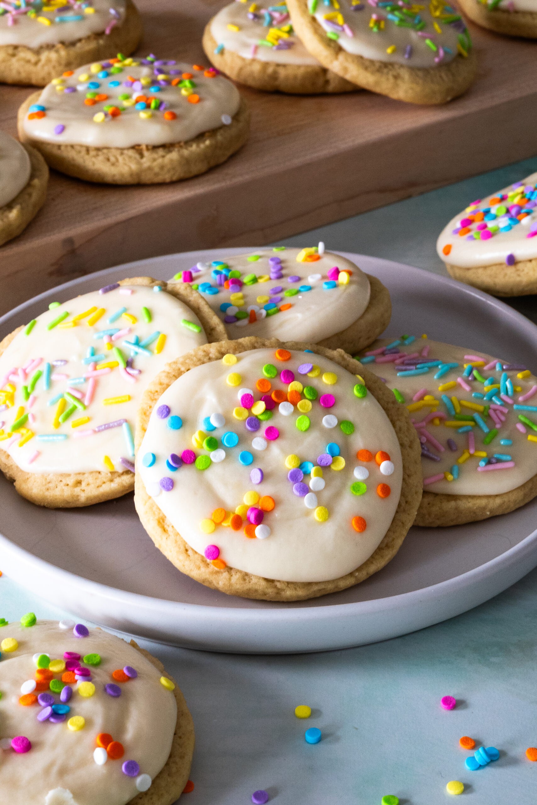 colorful sprinkle sugar cookies with creamy white frosting on a cooling rack