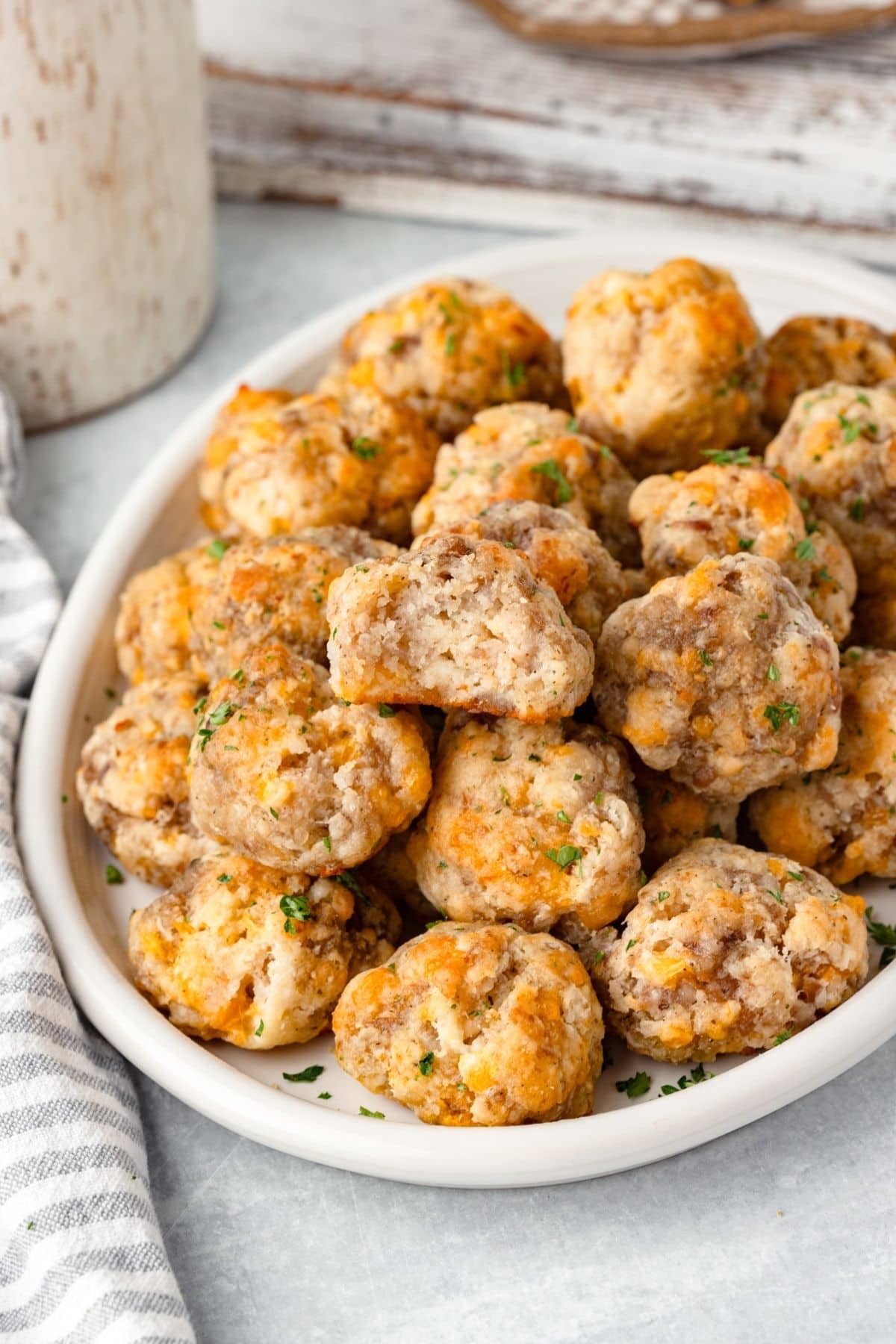 Golden brown cheddar sausage balls on a cooling rack, garnished with fresh parsley