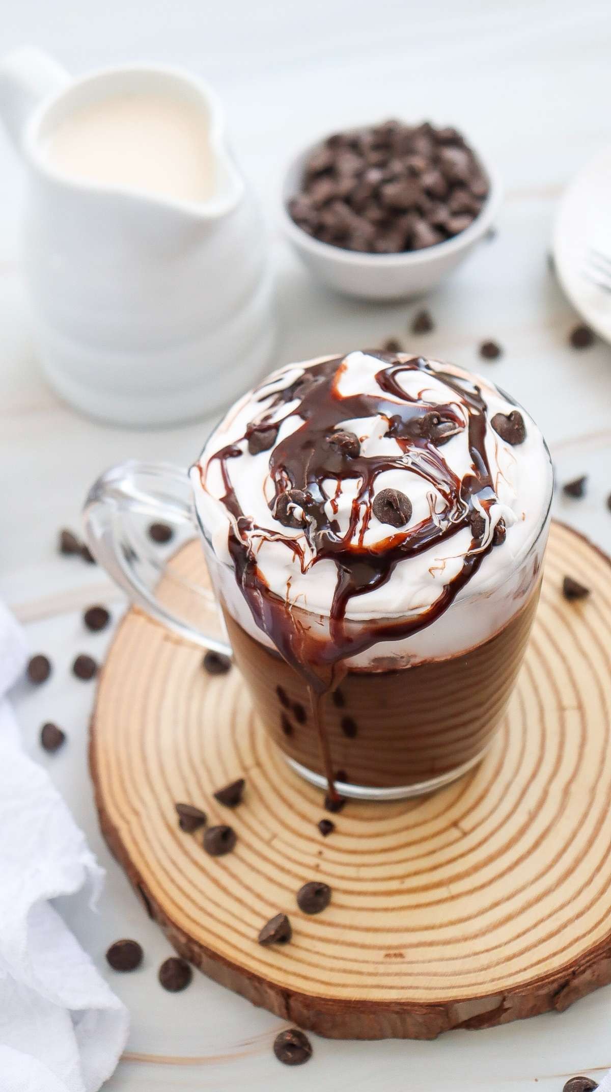 steaming mug of deep mocha hot chocolate with coffee beans and chocolate shavings on top, cozy setting