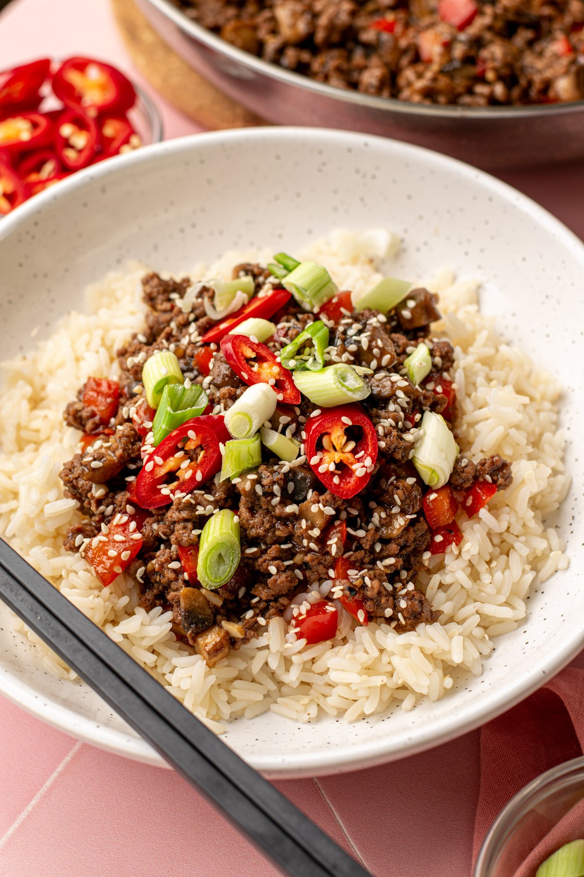 Vibrant chili beef bowl with fluffy white rice and fresh toppings, cozy kitchen setting, natural light