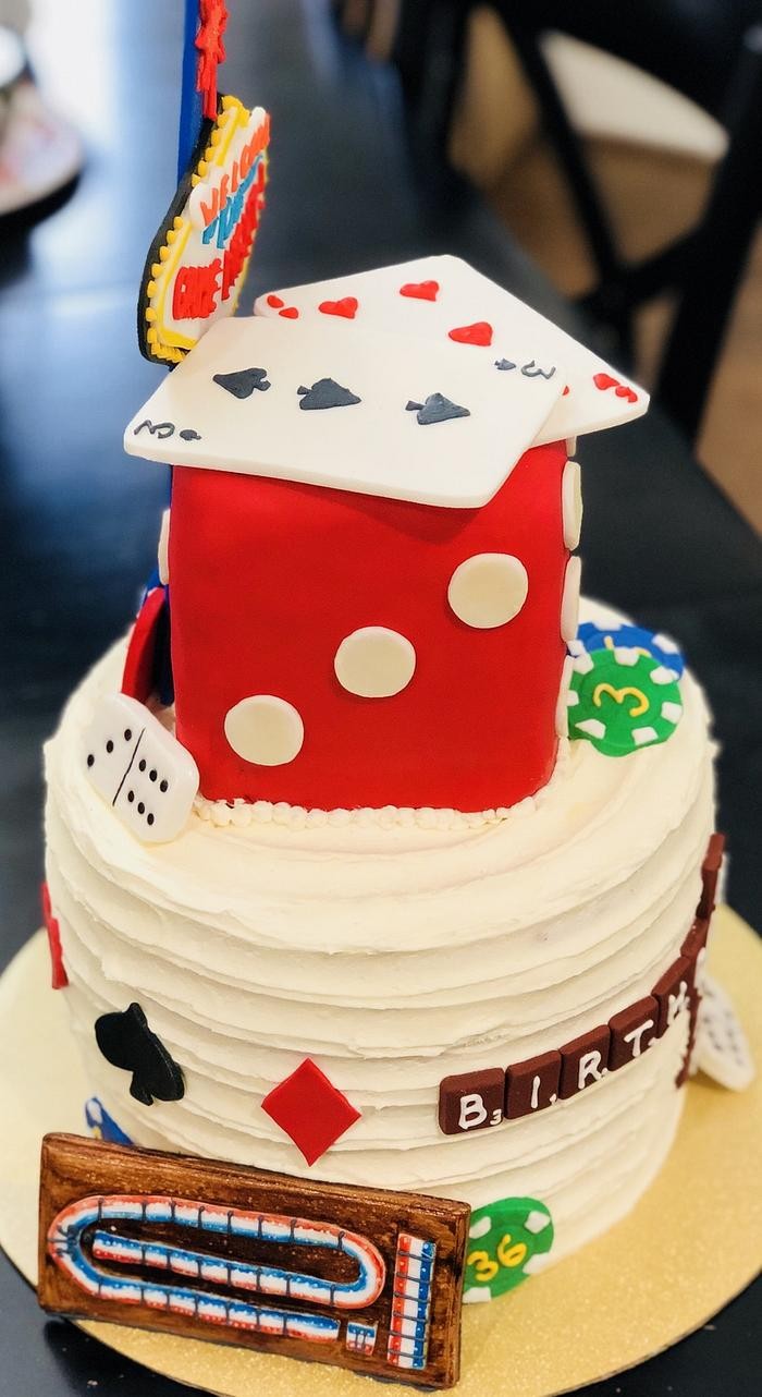 a beautifully decorated vanilla birthday cake with game night decorations