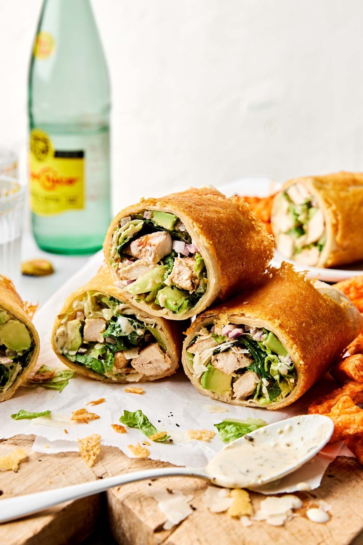 close up of mini chicken Caesar salad wraps on a plate, garnished with fresh herbs