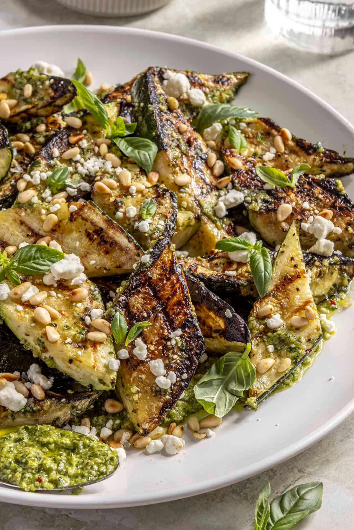 roasted zucchini slices topped with walnut pesto, garnished with fresh basil