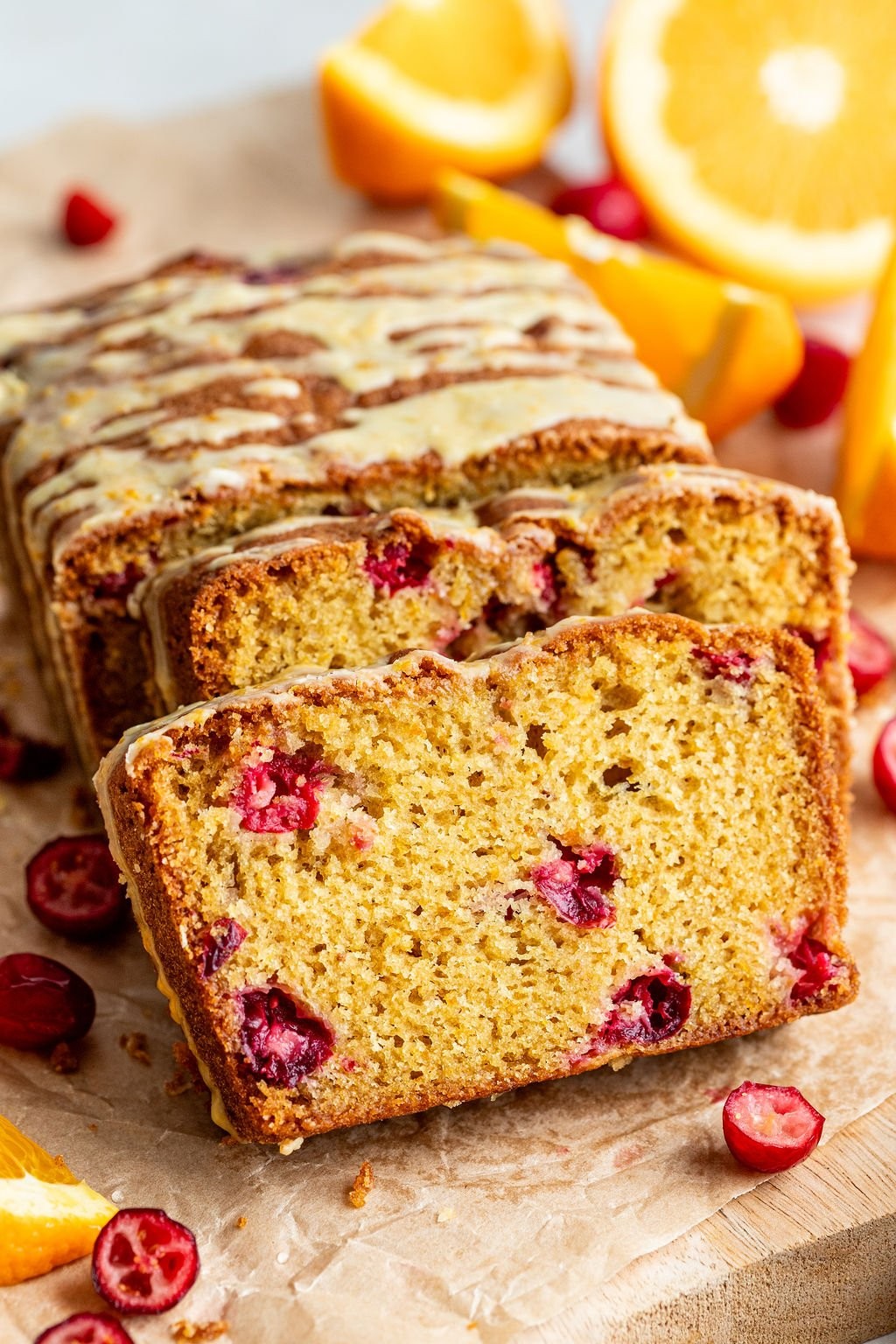 Vibrant cranberry orange bread loaf with shiny citrus glaze on a rustic wooden board, natural light, cozy kitchen background