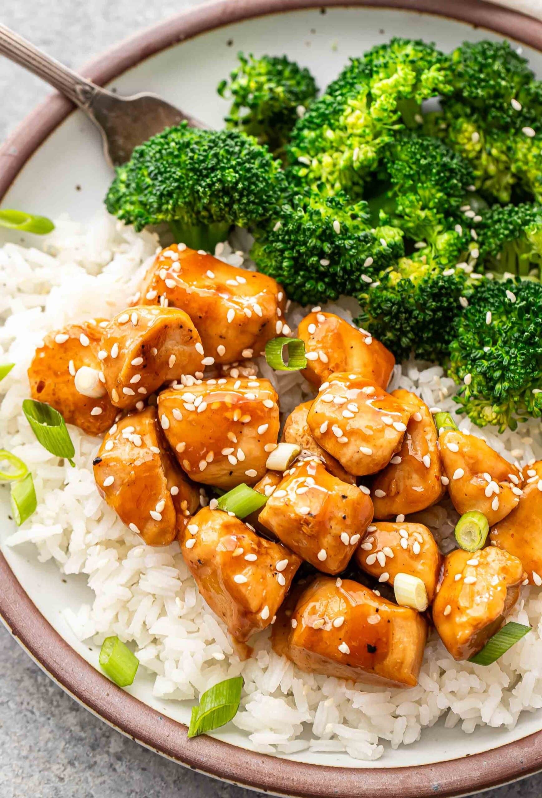 Delicious sticky teriyaki chicken served with rice and broccoli, garnished with sesame seeds