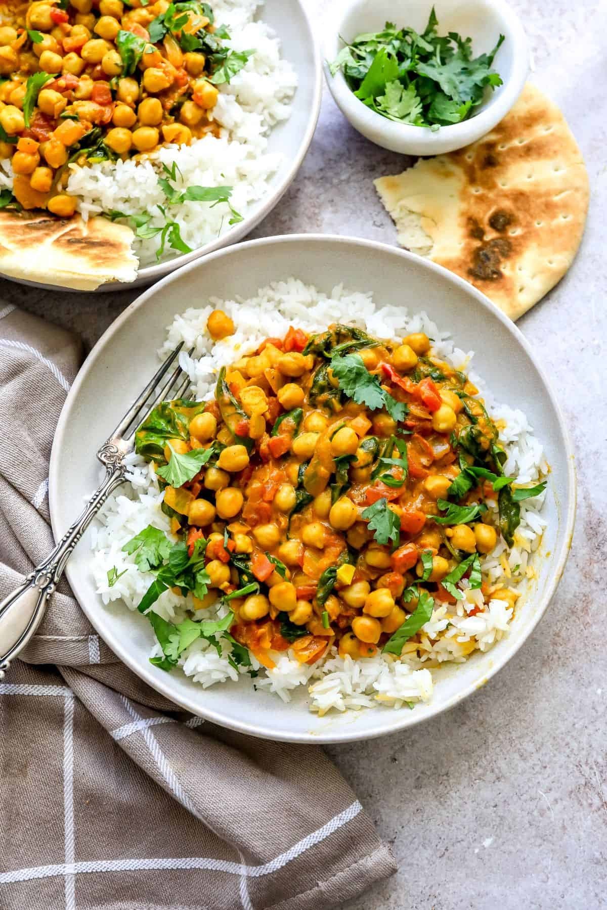 Vibrant chickpea spinach curry in a rustic bowl, steaming, with fresh cilantro and naan bread on the side