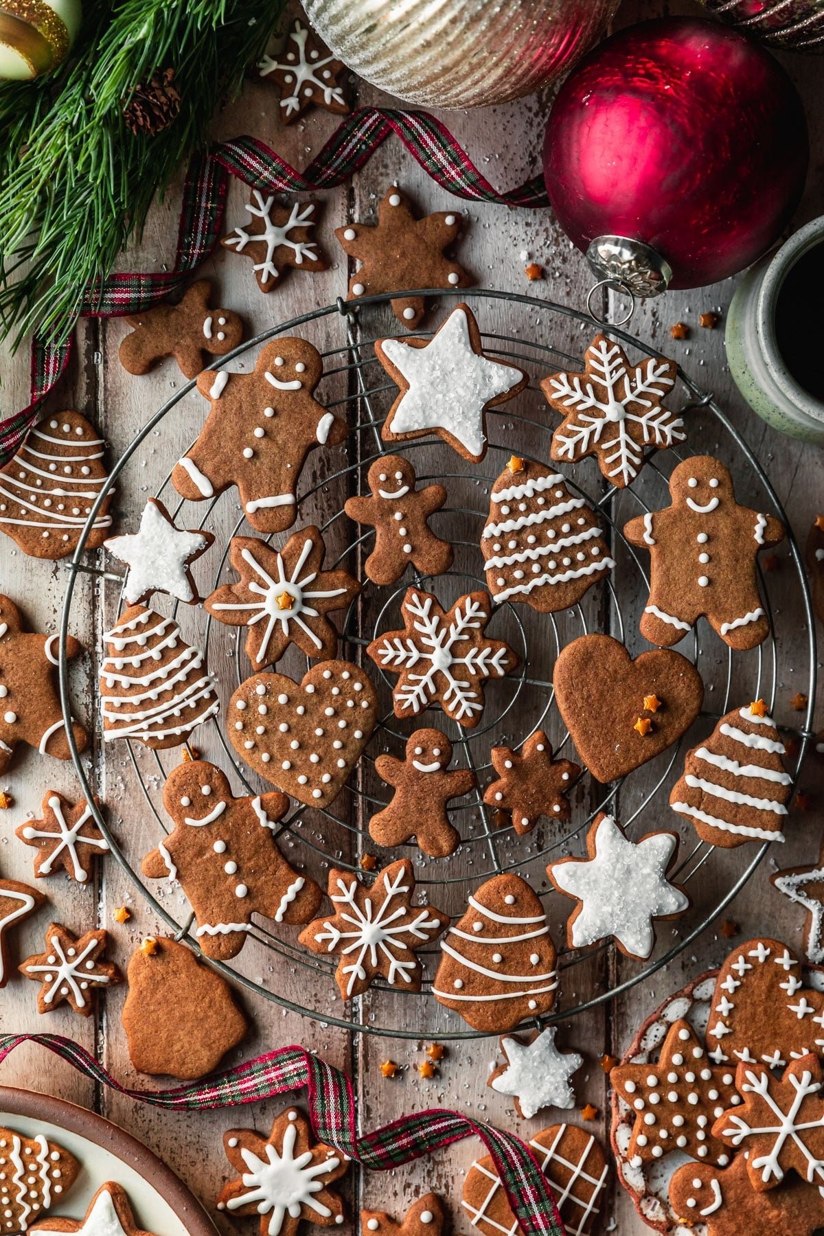 Festive gingerbread cookies with intricate white icing designs on a wooden table, cozy holiday setting