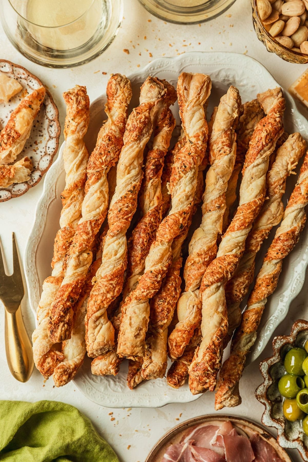 Golden brown savory parmesan puff pastry twists cooling on a wire rack with a side of marinara sauce