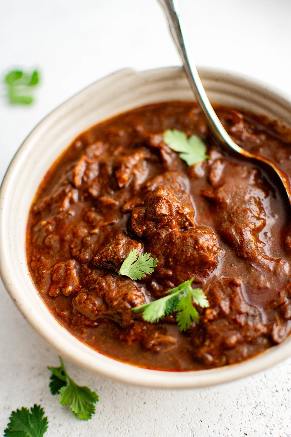 Close-up of chili-fired skillet beef, garnished with fresh cilantro and lime wedges, steaming, rustic kitchen setting