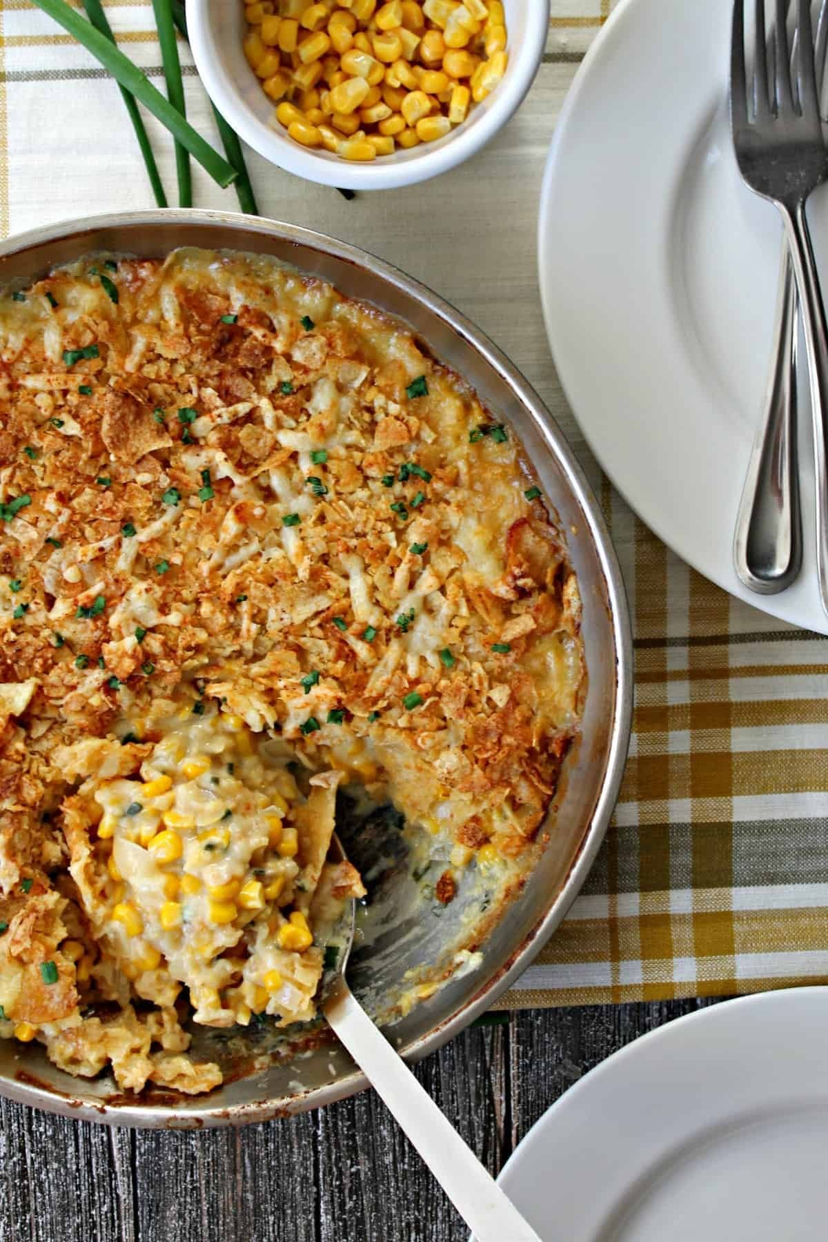 Warm golden baked corn casserole, garnished with fresh chives, rustic kitchen setting