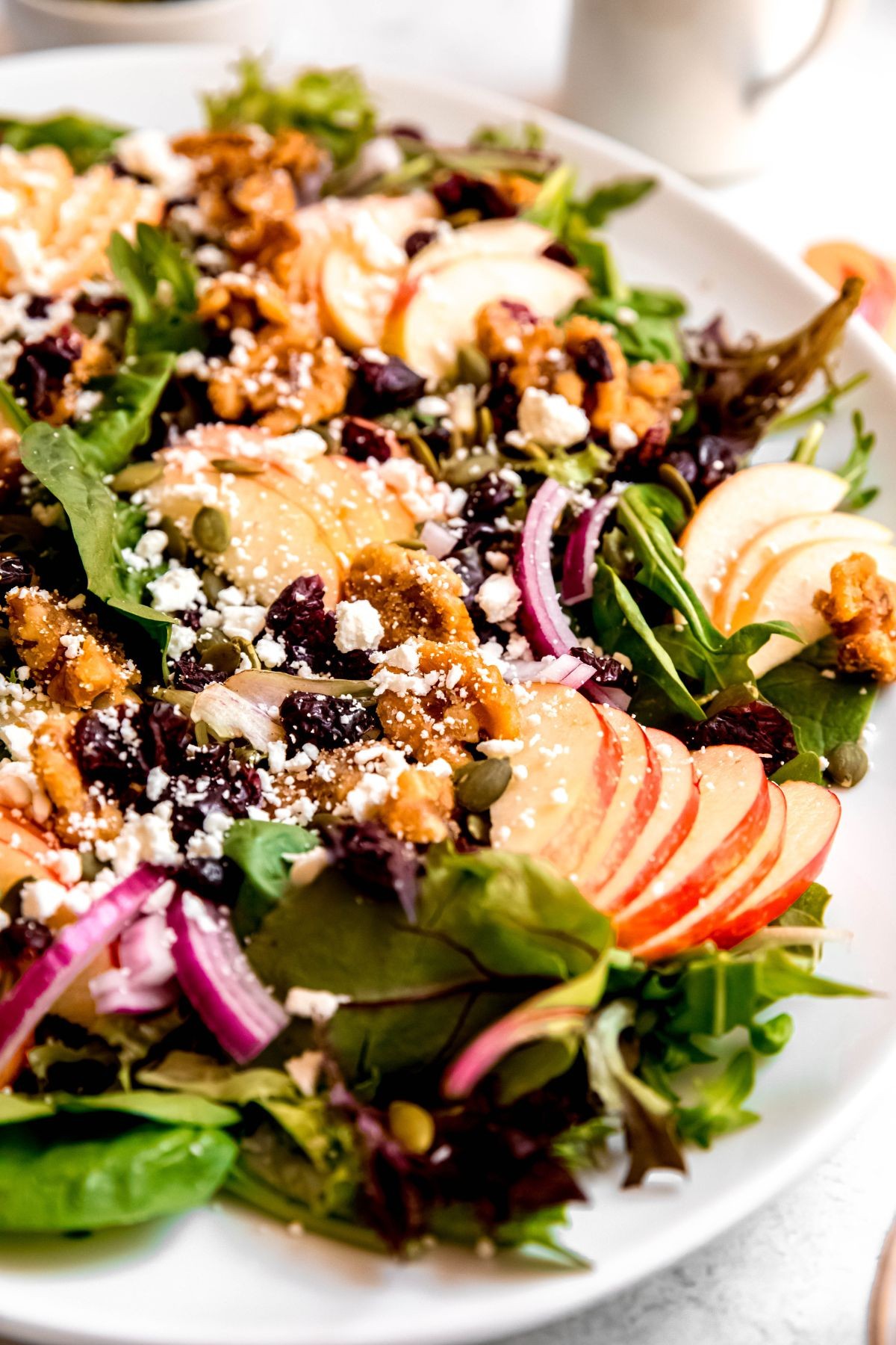 Vibrant close-up of fresh apple walnut salad with honey drizzle on a light wooden background