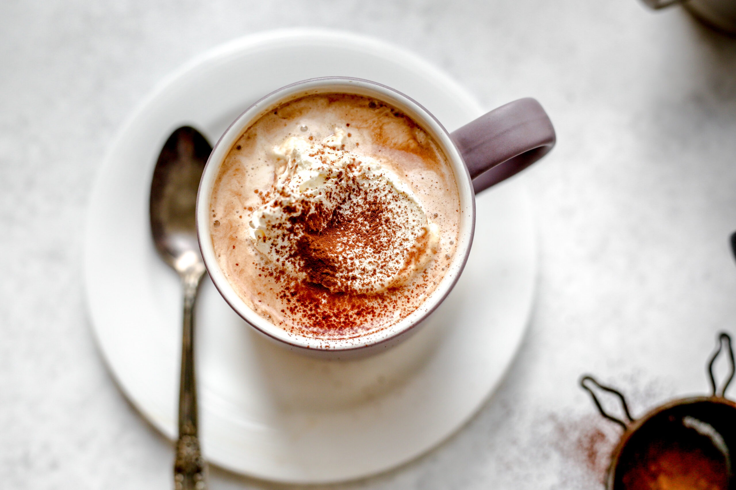 Steaming mug of light almond milk hot chocolate with cocoa powder dusting, cozy kitchen setting, soft lighting