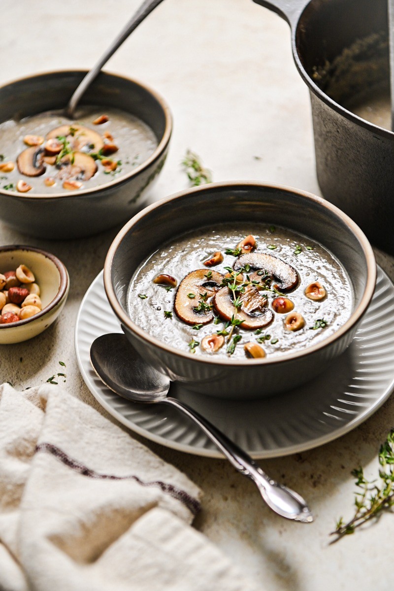 Warm bowl of creamy herb soup with crusty bread, cozy kitchen setting, soft lighting