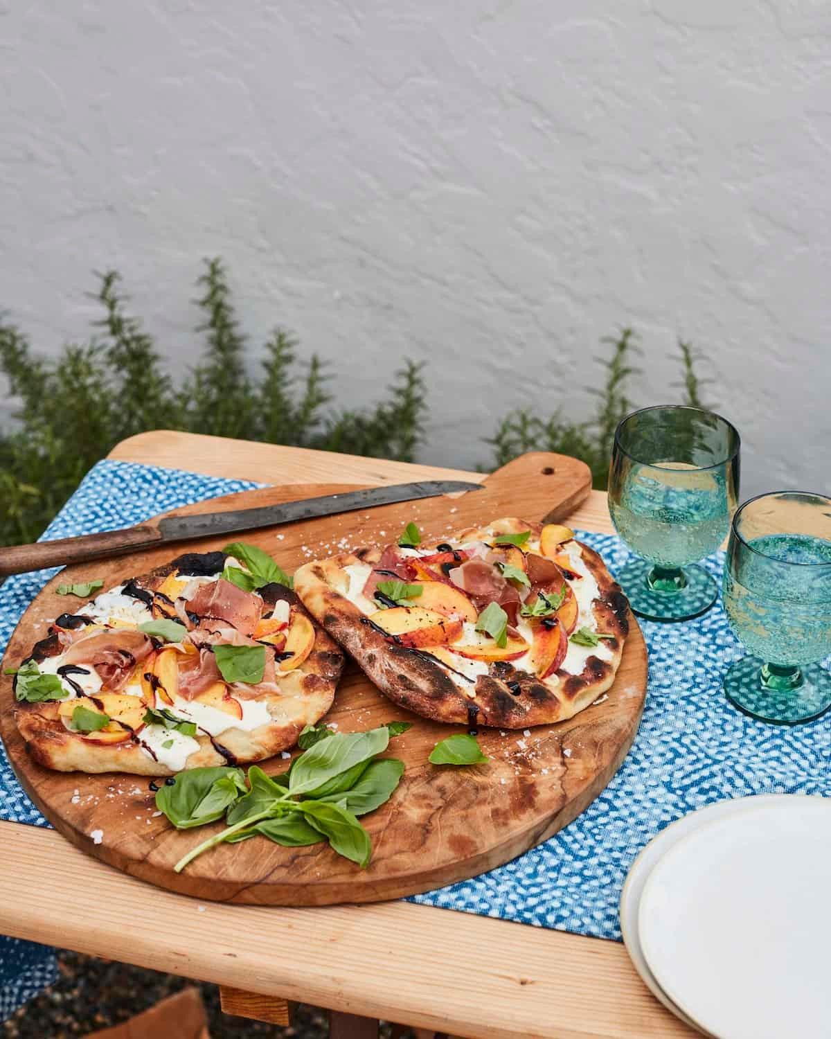 grilled peach prosciutto pizza on wooden board