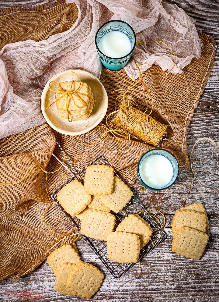 Golden shortbread cookies cooling on a wire rack, with a vintage kitchen towel and a cup of tea in the background