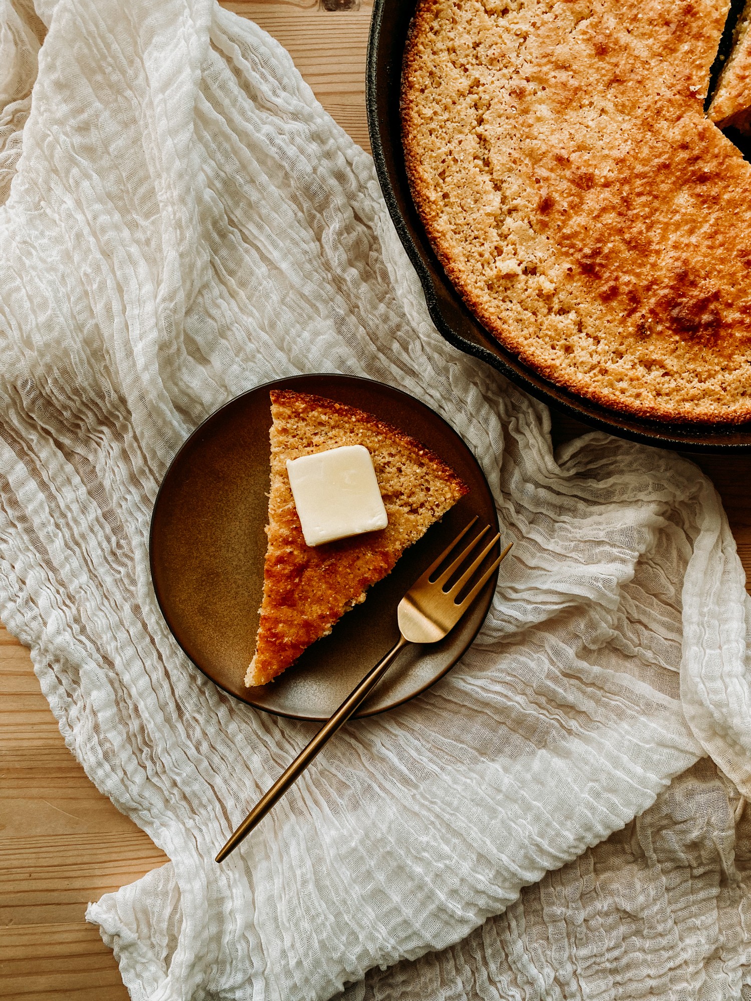 golden skillet cornbread slice with butter on a wooden board