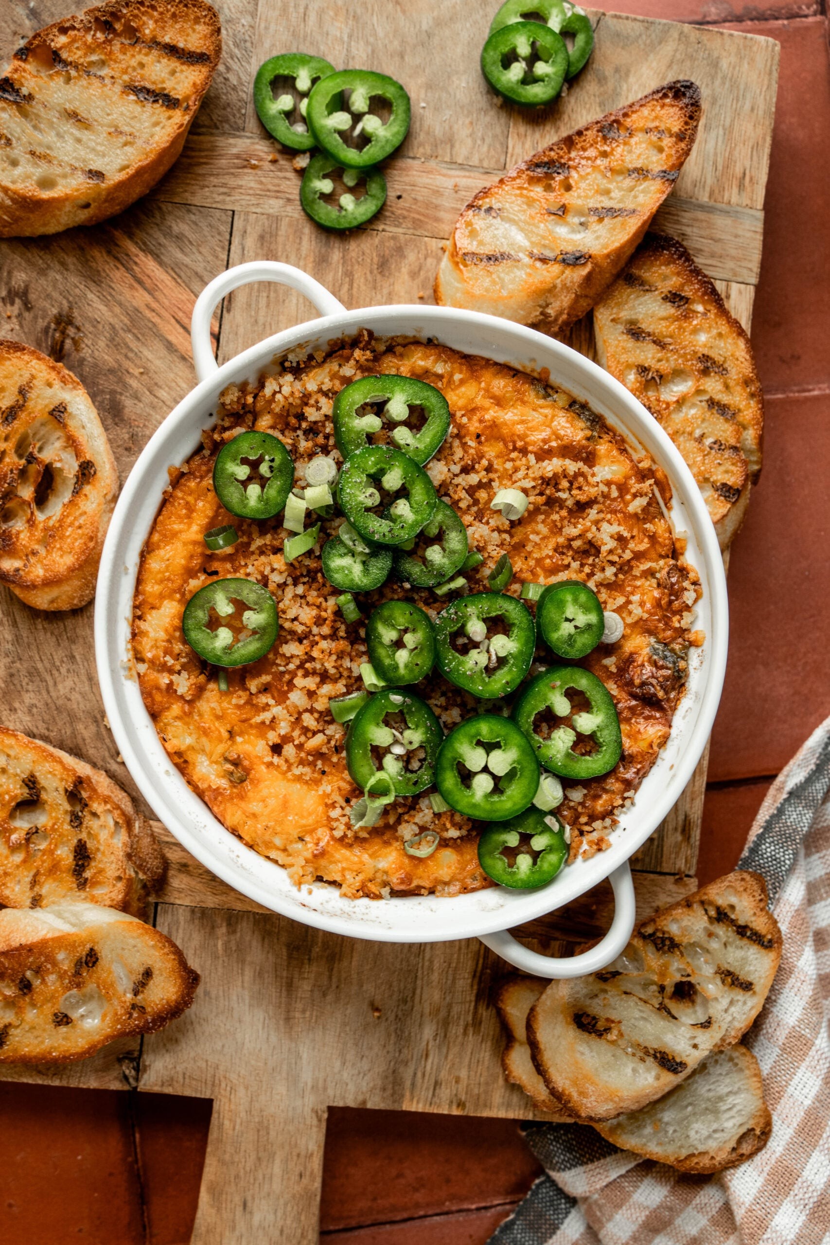 creamy baked jalapeño popper dip in a rustic bowl with crackers and fresh jalapeños