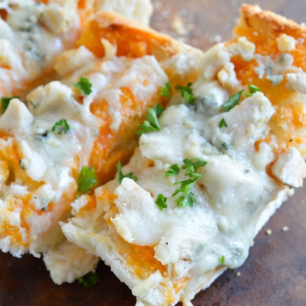 overhead shot of cheesy buffalo chicken tear-away bread on a rustic wooden board, garnished with chives and a side of blue cheese dip, perfect for a party