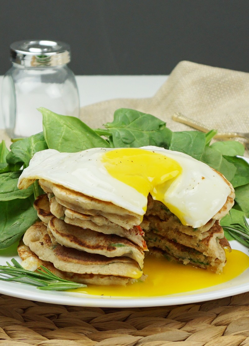 sun-dried tomato cottage cheese pancakes stacked on a plate with herbs