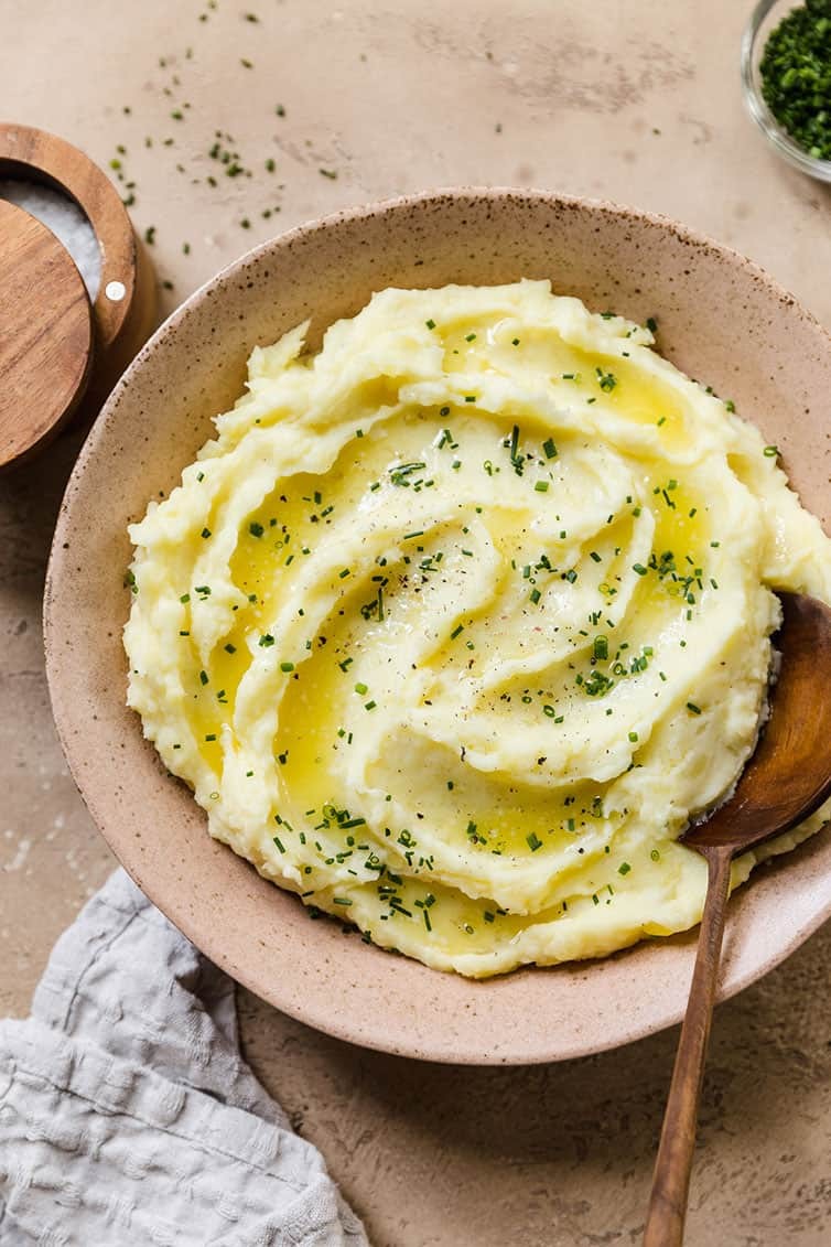 beautifully plated creamy mashed potatoes with melted garlic butter and herbs, holiday setting