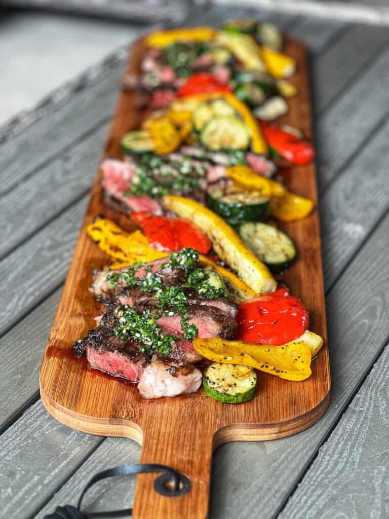 grilled garlic parmesan flank steak on a wooden cutting board