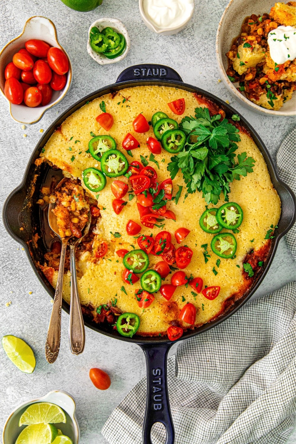 Rustic corn casserole in a cast iron skillet, golden brown and bubbly, garnished with fresh chives, on a wooden table with a cozy setting.