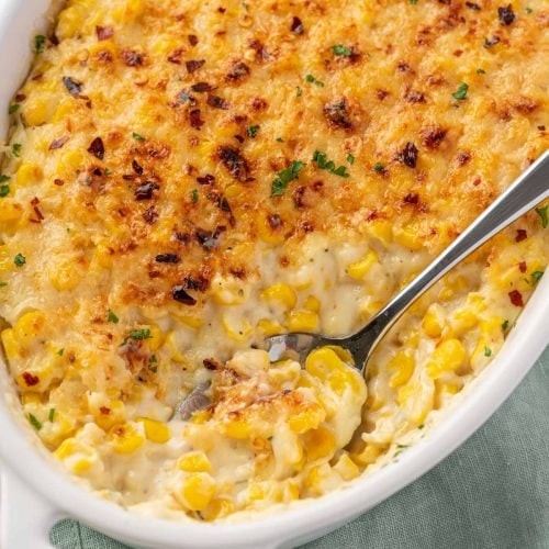 Delicious creamy corn casserole served in a baking dish with a spoon, steam rising