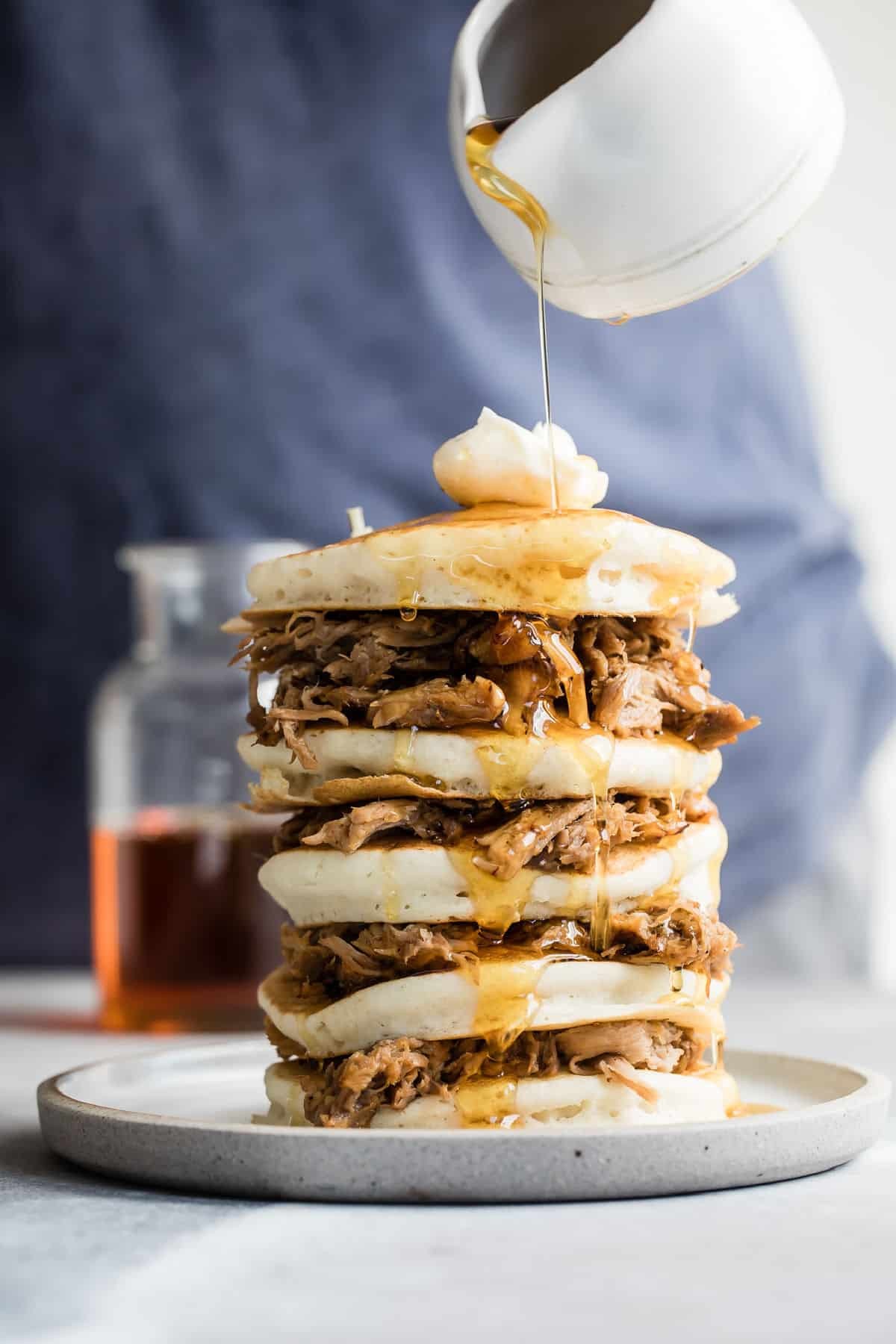 stack of chai-spiced pulled pork pancakes topped with maple syrup and cinnamon
