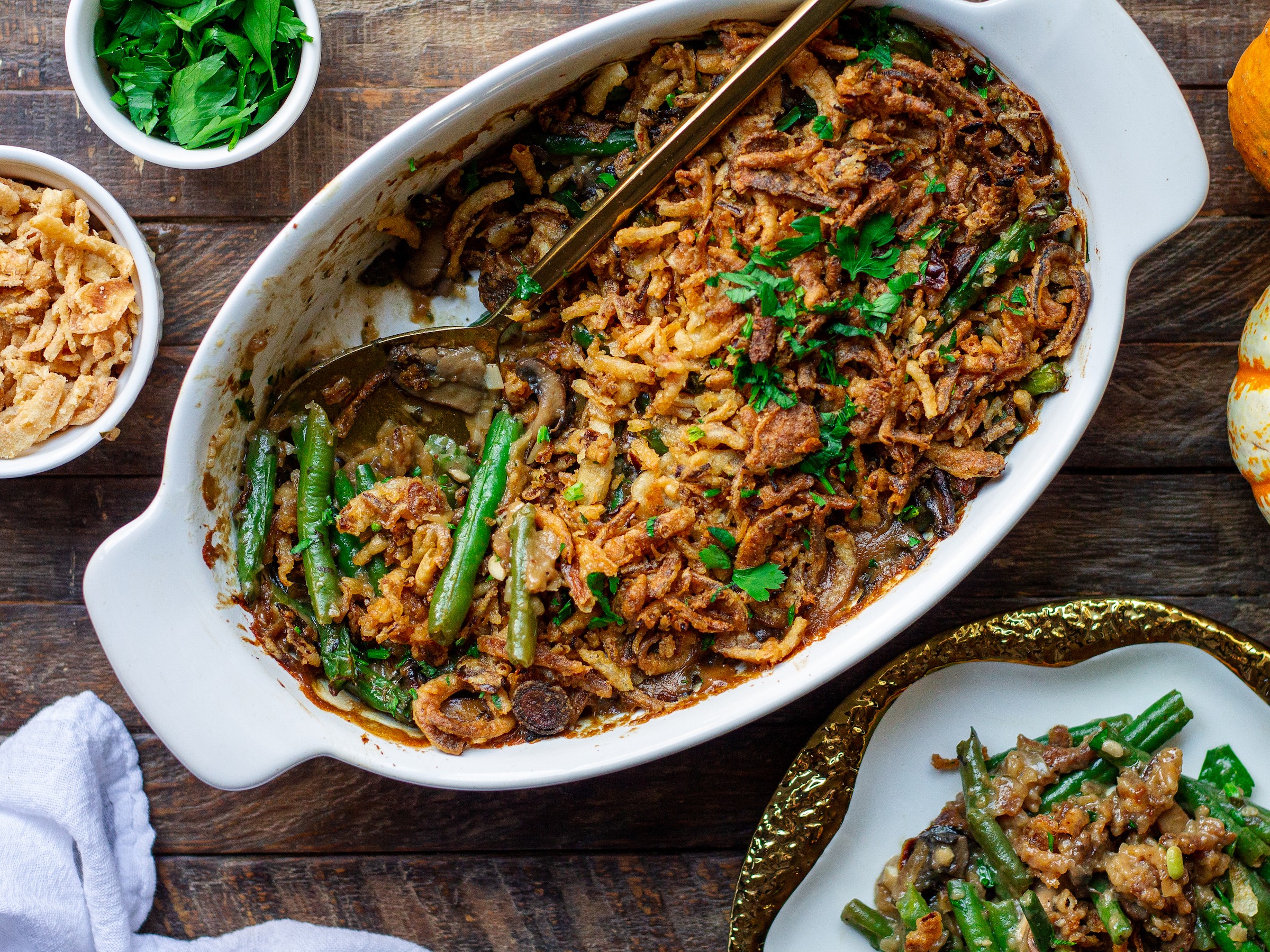 close-up, vibrant green bean casserole with creamy pepper sauce and crispy onions on top, holiday dinner table setting