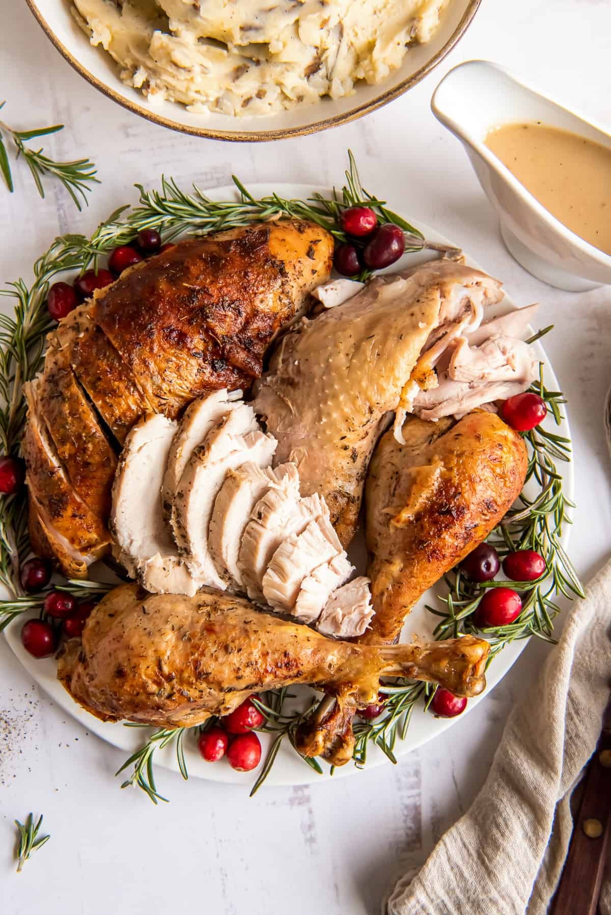 beautifully roasted golden-brown turkey with fresh rosemary sprigs and a side of cranberry sauce on a festive table
